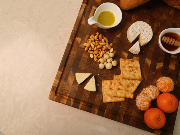 End-grain teak cutting board styled with cheese, crackers, nuts and mandarins
