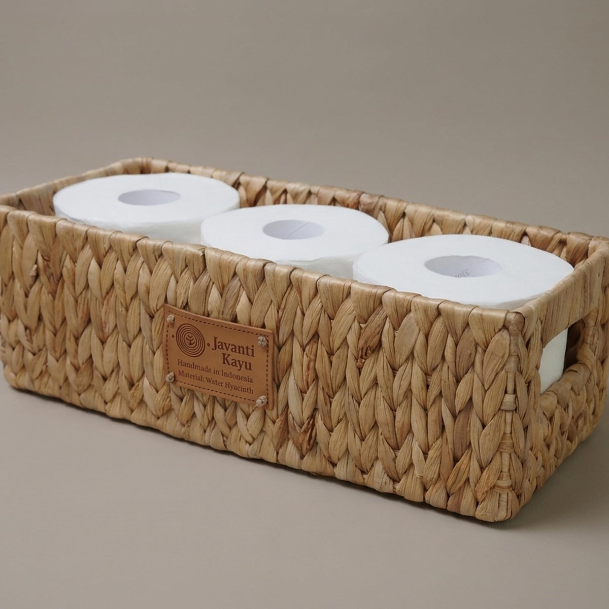 Long basket holding three spare toilet paper rolls