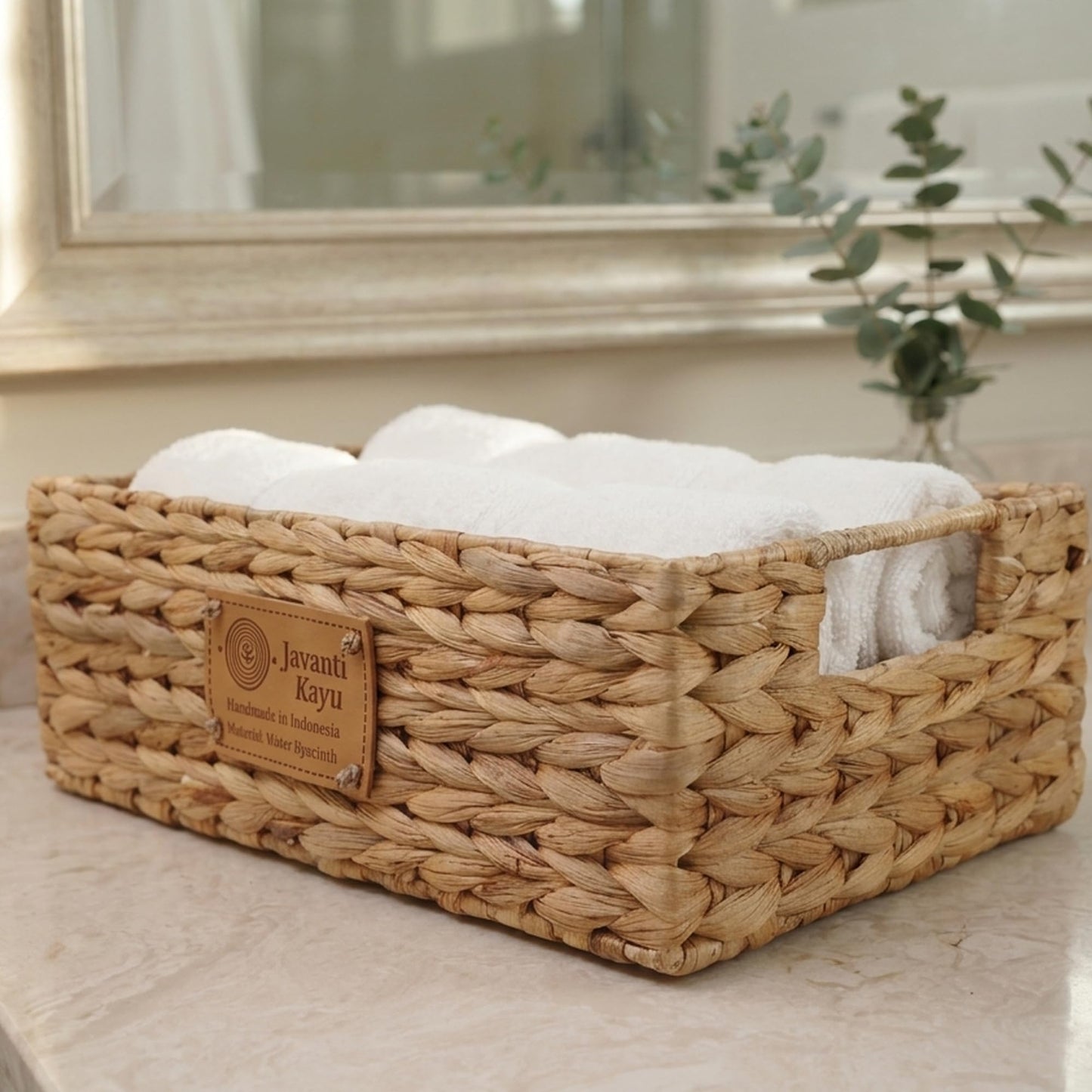 Small basket on a bathroom counter with folded white towels