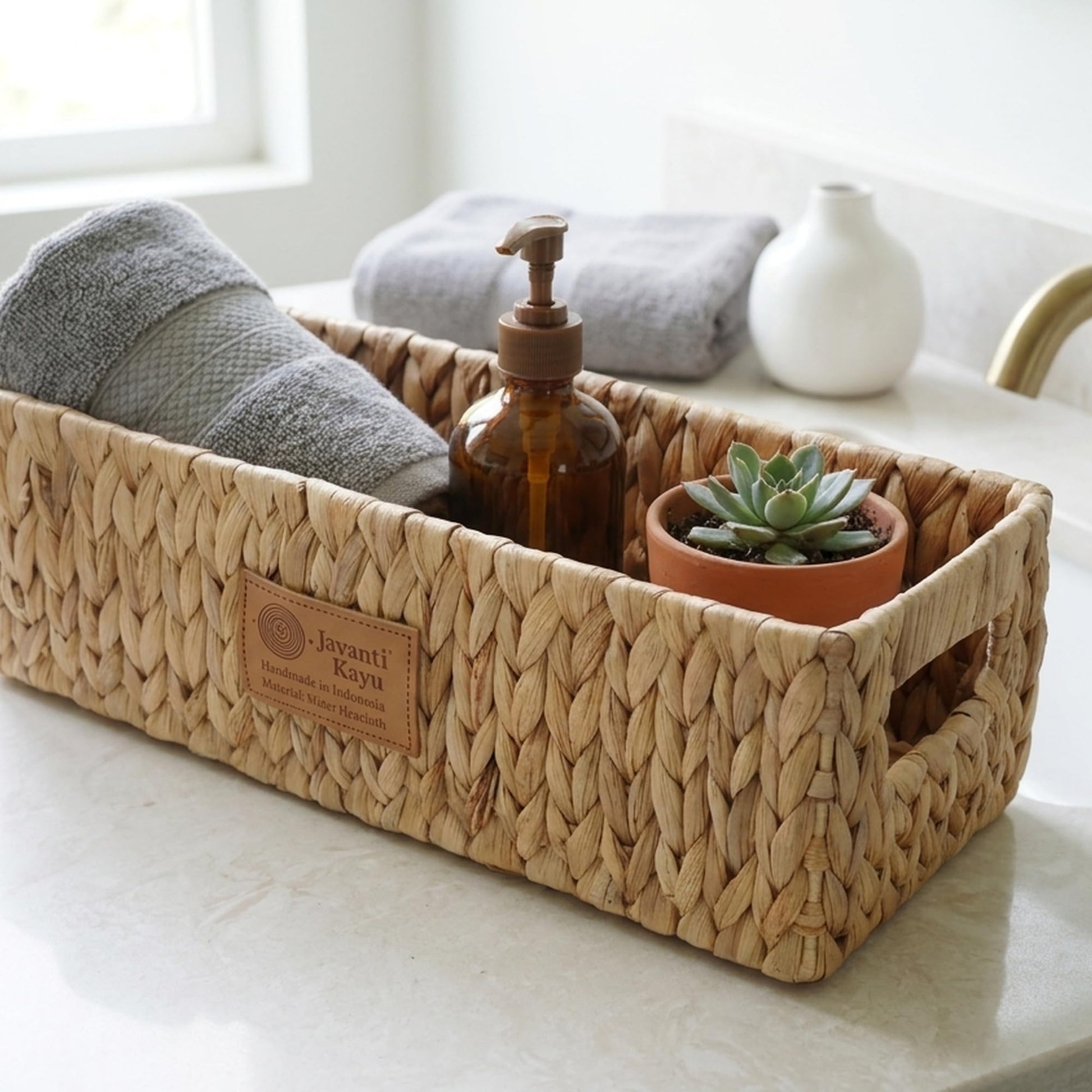 Long basket on a bathroom shelf with a rolled towel, soap pump and a small plant