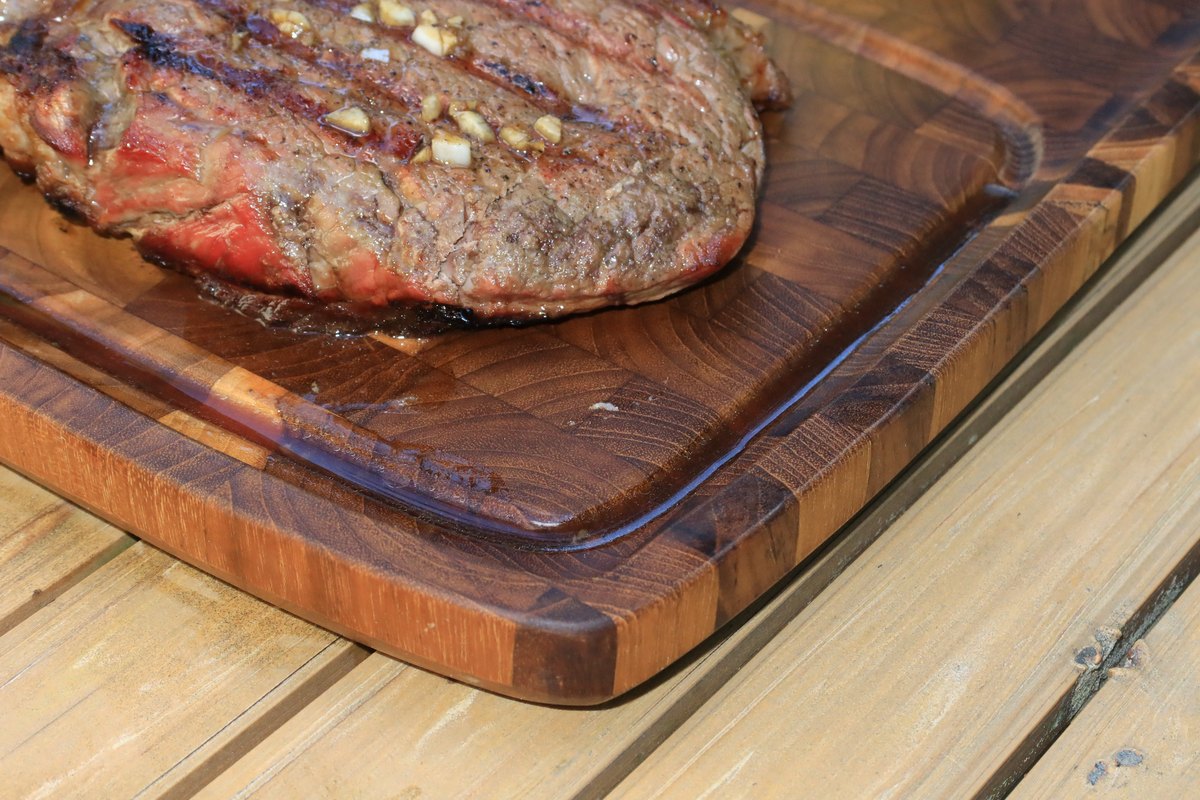 Deep juice groove around a steak on a teak plate